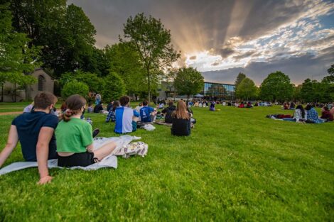 Students sit on the Quad, watching Jerry Greenfield speak.
