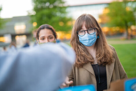 A student wearing a mask takes a pint of ice cream.