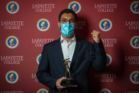 Yazdan Basir '23 holding Aaron O. Hoff Award statue and standing in front of Lafayette College backdrop
