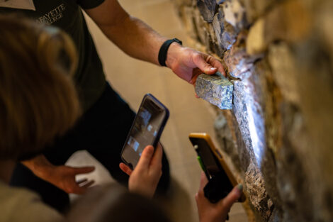 students in masks look at Van Wickle geology rock walll