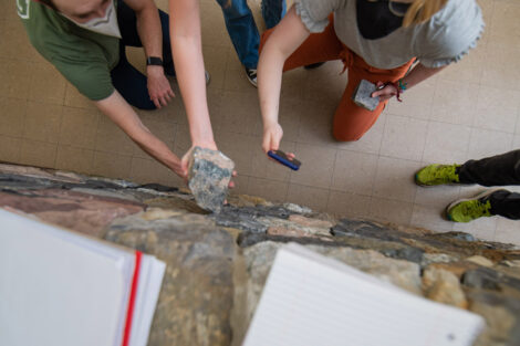 students in masks look at Van Wickle geology rock walll