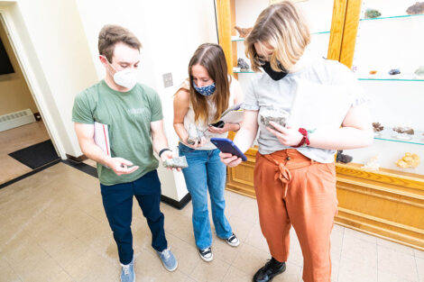 students in masks look at Van Wickle geology rock walll