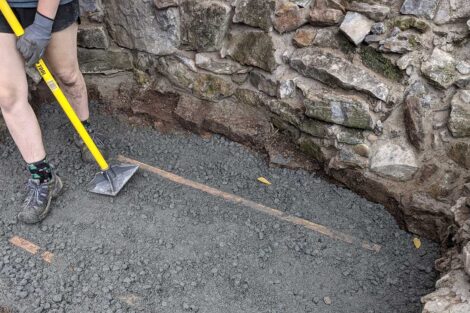 A student tamps down the material to make the fire pit floor even