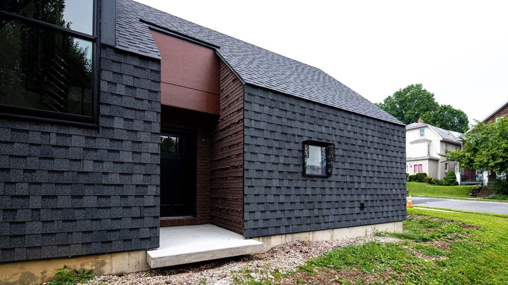 Side view of home featuring front door and asphalt shingles on roof and sides 