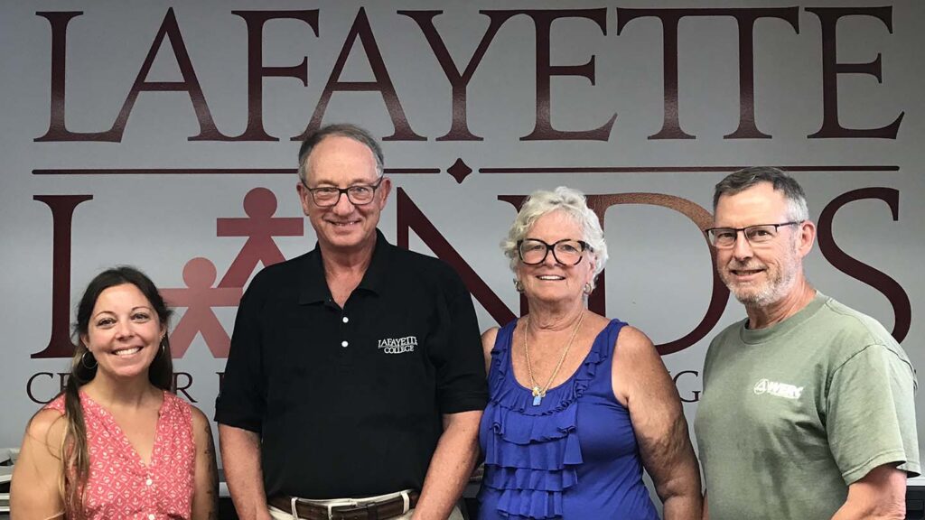 Thomas and Sharon Smith stand with Landis leaders Chelsea Cefalu and Art Kney with Landis logo in backdrop