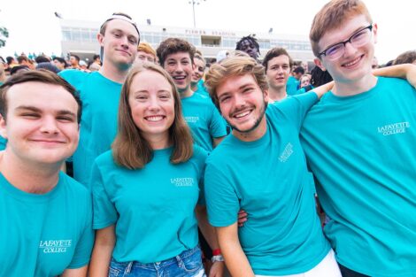 students in matching blue Tshirts smile in Fisher Field stands
