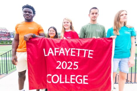 five students hold Lafayette College 2025 banner with Fisher Field in background