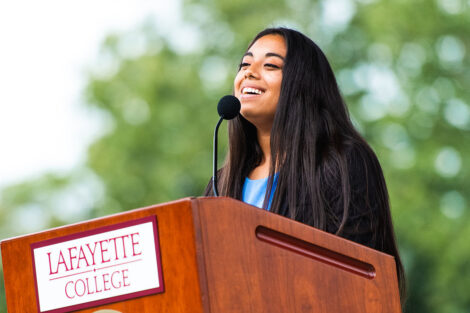 student government president Flor Caceres stands at podium and smiles