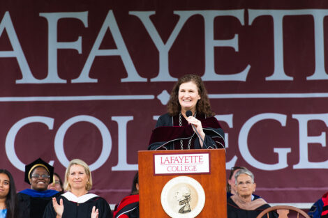 President Nicole Hurd stands at podium and smiles, Lafayette College banner is backdrop
