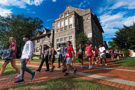 orientation group of new students walk in front of Hogg Hall, sky is a brilliant blue