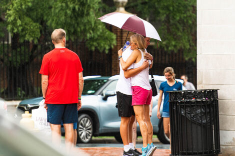 Lafayette student holding umbrella hugs mom goodbye