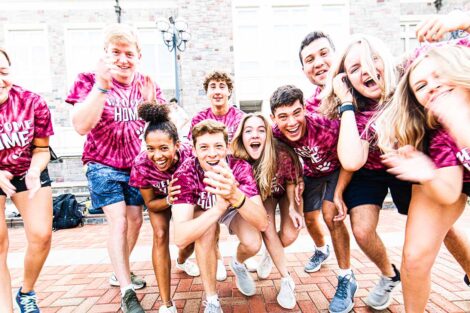 group of students in Welcome home tie-dye shirts smile outdoors