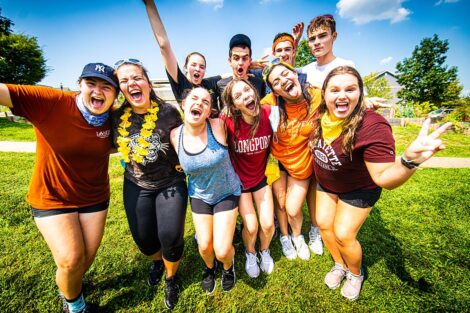 Students pose in a celebratory manner outside.