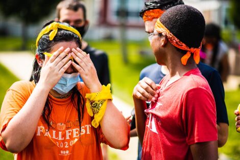 A student covers her eyes as if hiding in front of a younger child.