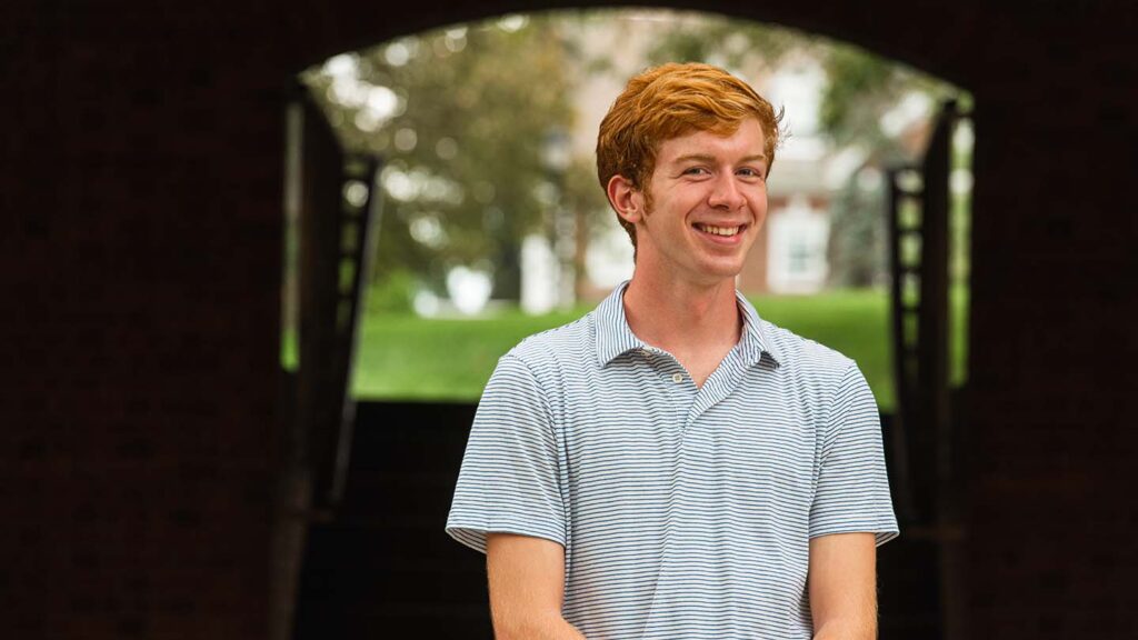 Colin stands under an archway at Ruef Hall