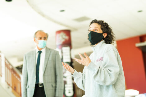 Both wearing masks, Delcia Nahman speaks next to Bruce Ferretti