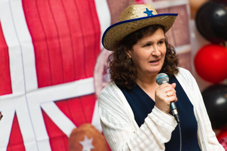 President Hurd, wearing a cowboy hat, speaks into a microphone.
