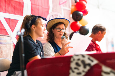 President Nicole Hurd, alongside a student, reads trivia while holding a microphone.