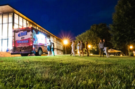 An ice cream truck sits on the Quad outside of Skillman Library, with a line of students.