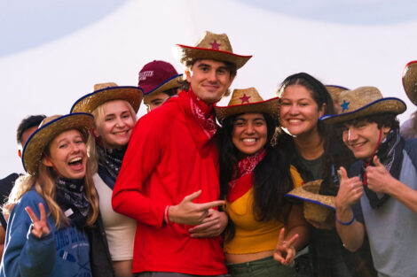 Students smile, wearing cowboy hats and bandanas.