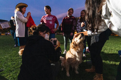 Students and Nicole and Bill Hurd stand around a golden retriever on the Quad
