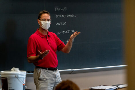 Professor Ethan Berkove, masked, instructs his students in front of a chalkboard.