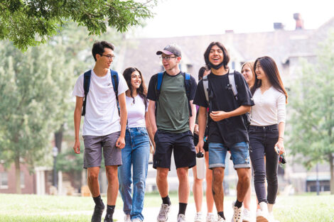 A group of students walk and engage in conversation outside of Hogg Hall.