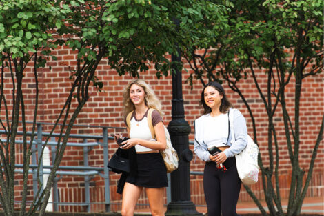 Two students smile as they walk.