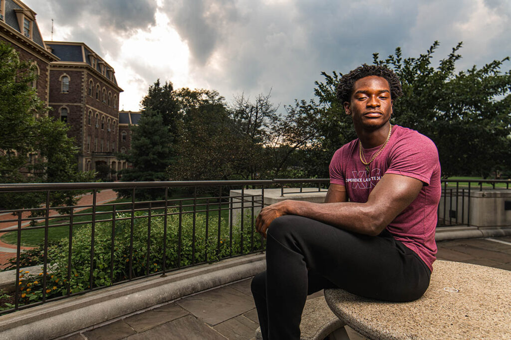 Kwesi Obeng-Danka on a table outside of Farinon College Center, in front of Pardee Hall.