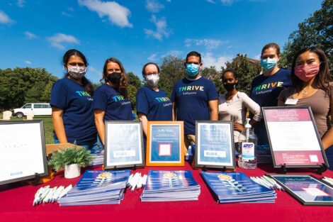 Counseling Center staff wears masks and stands at Thrive table at Quad event