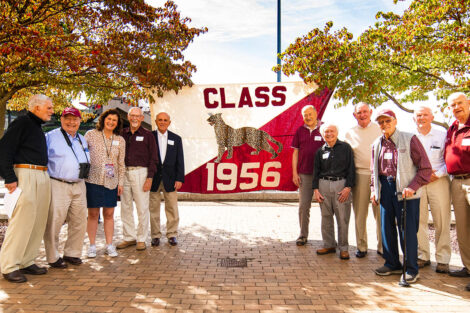 Members of the Class of 1956 stand in front of a flag.
