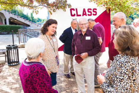 Members of the Class of 1956 stand in front of a flag.