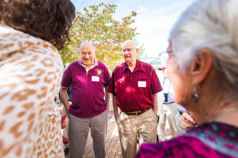 Members of the Class of 1956 stand in front of a flag.