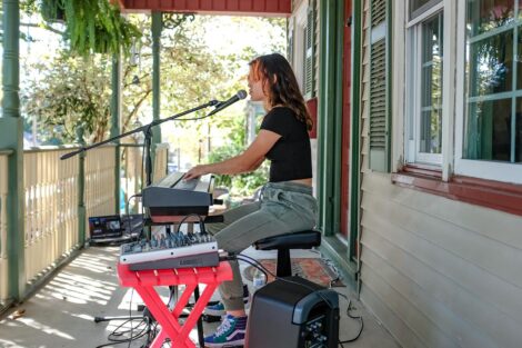 young person plays keyboard and sings on a porch