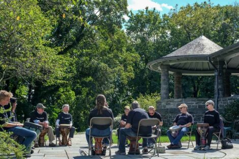group of percussionists sit in circle with drums