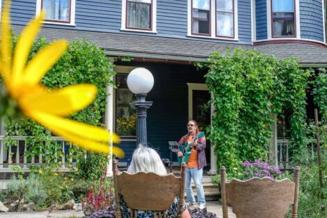 person plays guitar in front of a house