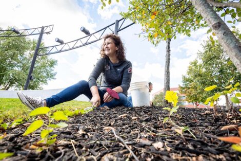 President Nicole Farmer Hurd sits in mulch of Riverside Park