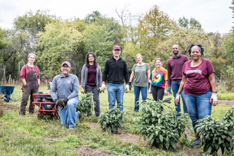 Staff volunteers smile, surrounded by a garden.