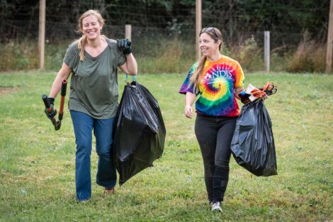 Two staff volunteers carry trash bags.