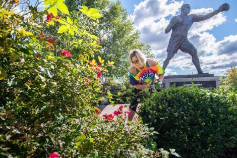 A staff volunteers in front of the Larry Holmes statue.
