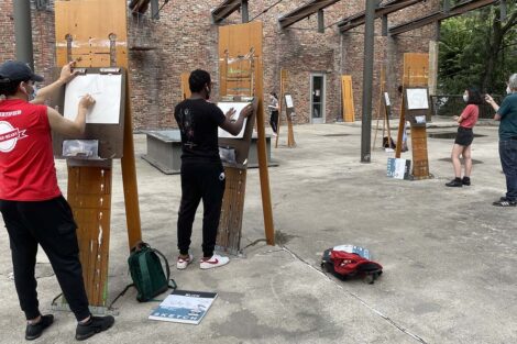 Prof. Pedro Barbeito speaks to students who are lined up a easels