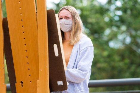 Student looks at object while standing at her easel
