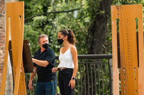 Prof. Jim Toia gives pointer to student as they stand a easel