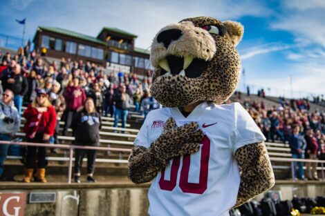 Leopard mascot stands with hand over heart on sidelines