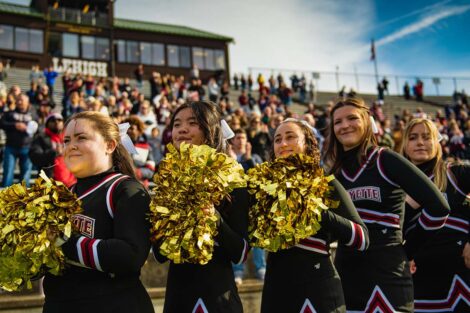 Lafayette student cheerleaders stand on the sidelines with golden pom-poms