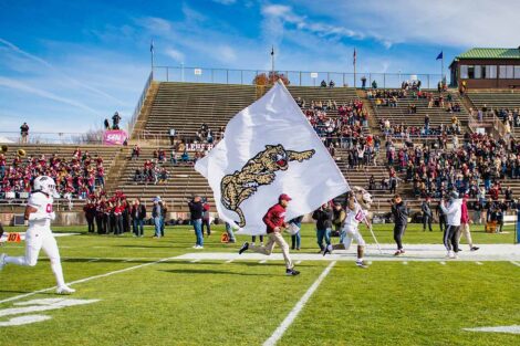 Leopard mascot carries a hug Leopard flag, leading the team in running out on the field