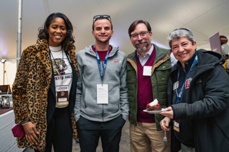 Sherryta Freeman, John Meier, Annette Diorio gather and smile under a tent