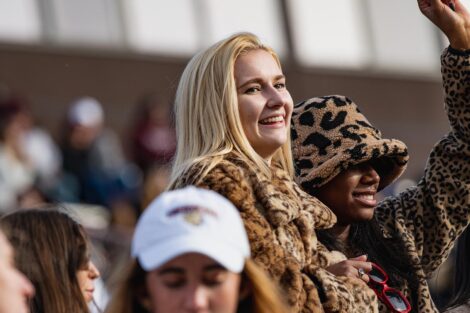 students in leopard print outfits cheer from stands