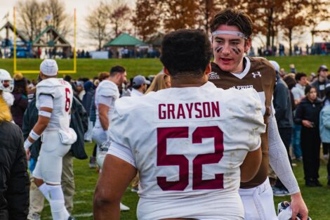 Grayson #52 shakes the hand of a Lehigh football player on the field
