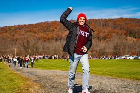person in Lafayette sweatshirt smiles and raises fist heading toward the stadium